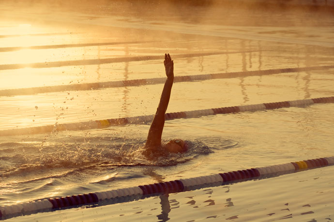 A backstroke swimmer training early in the morning in the morning sun