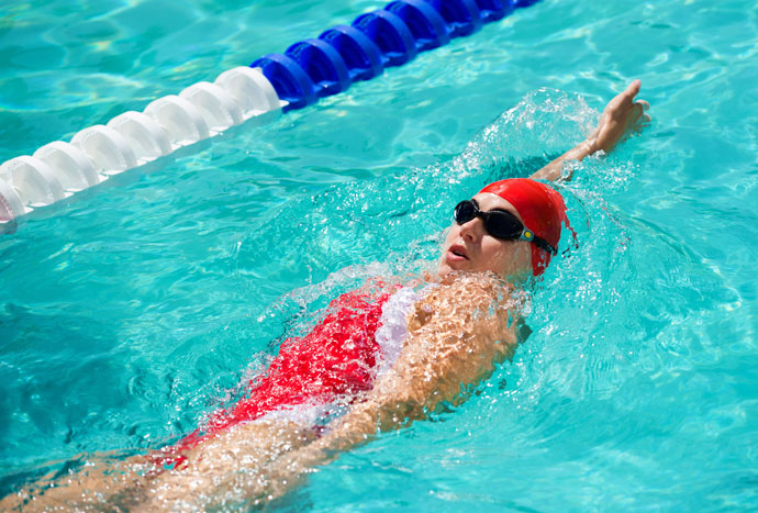A woman swimming backstroke with arm extended overhead