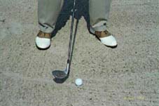 Close of up ball in sand, with wedge alongside