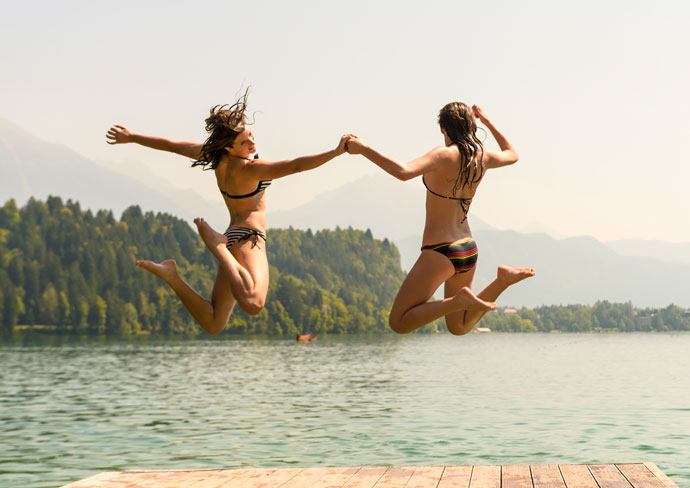 Two girls jumping into a lake