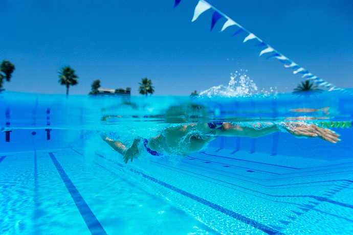 A man swimming in an open-water pool on a sunny day