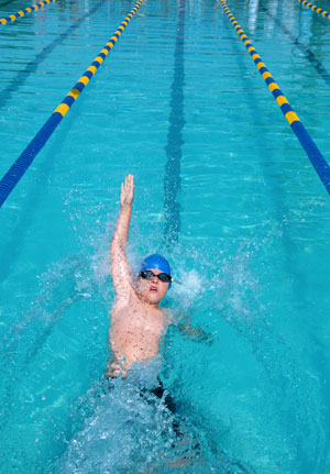 A young boy swimming backstroke
