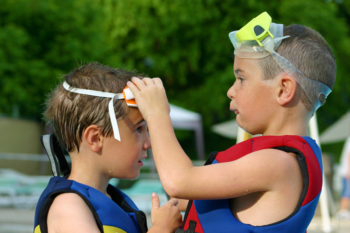 Older brother adjusting the swim goggles of his younger brother